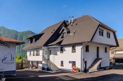 a large white house with a brown roof at Penzion Hosnar, apartma Mucho in Bovec