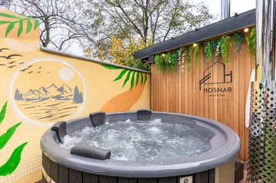 a hot tub in front of a wall with a sign at Penzion Hosnar, apartma Mucho in Bovec