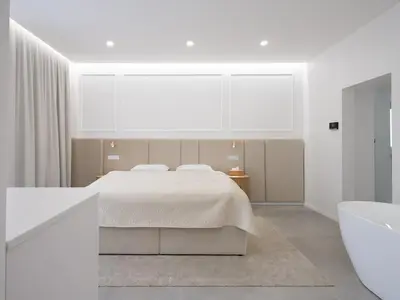 a white bedroom with a bed and a bath tub at Trend Apartment in Ormoz