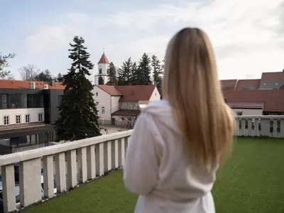 a woman standing on a balcony looking at a church at Trend Apartment in Ormoz