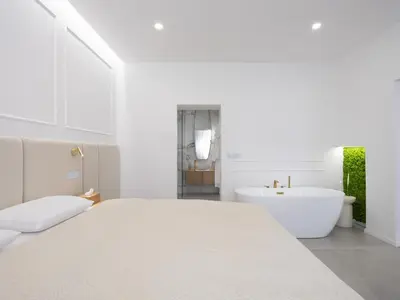 a white bedroom with a white bed and a bath tub at Trend Apartment in Ormoz