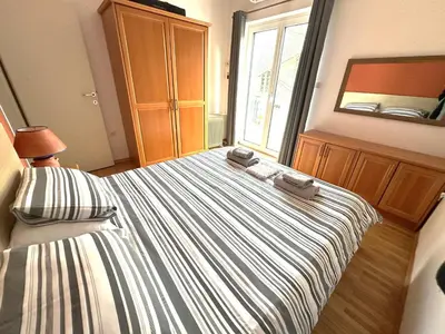 a bedroom with a striped bed with a mirror at Apartma Angela Bled in Bled