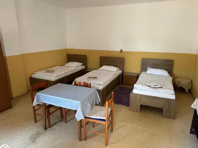 a room with two beds and a table and chairs at Soba Pri Kosu in Slovenska Bistrica