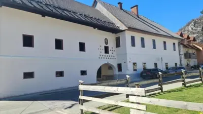 a white building with a fence in front of it at Apartmaji Despotoski Mojstrana in Mojstrana
