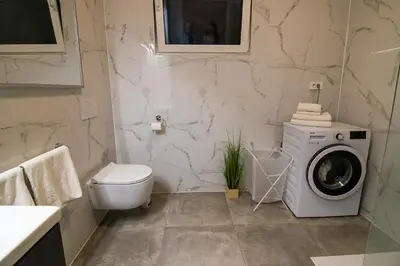 a bathroom with a washing machine and a toilet at Apartments Villa Prod in Ljubljana