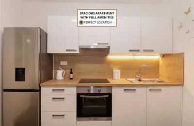 a kitchen with white cabinets and a sink and a refrigerator at Secret Corner in Ljubljana