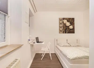 a white bedroom with a bed and a desk at Secret Corner in Ljubljana