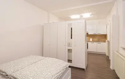 a white room with a bed and a kitchen at Secret Corner in Ljubljana