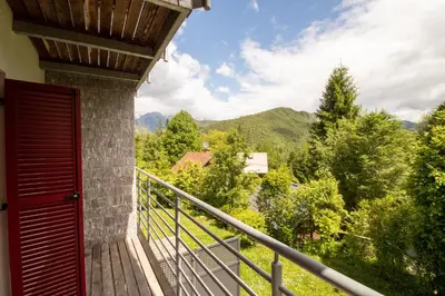 a balcony with a red door and a view of trees at Bohinj Cozy Escape Holiday Home in Bohinj