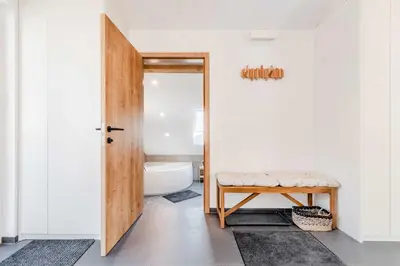a bathroom with a toilet and a stool next to a door at Alps2sea Apartment House in Srpenica