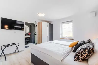 a bedroom with a large white bed and a window at Alps2sea Apartment House in Srpenica