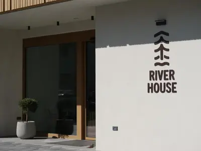 a building with a river house sign on the side of it at Bohinj River House Spa&Sport in Bohinj