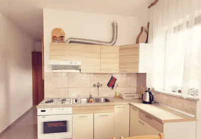 a small kitchen with white cabinets and a sink at Apartma Pristavica in Veliki Gaber