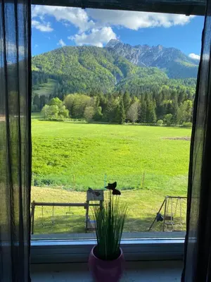 a window with a view of a field and mountains at Apartma Confine in Rateče