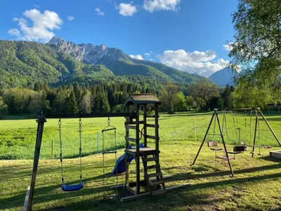 a playground with swings in a field with mountains at Apartma Confine in Rateče
