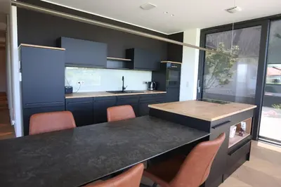 a kitchen with a black counter and orange chairs at Smart & Wellness Villa in Ptuj