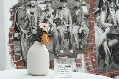 a white vase with flowers and a glass on a table at Layer Residences in Kranj