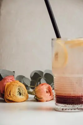 a glass of liquid next to three roses and a drink at Layer Residences in Kranj