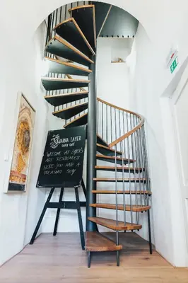 a spiral staircase with a sign next to a chair at Layer Residences in Kranj