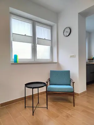 a room with a chair and a table and a clock at Apartma WALK in in Brežice