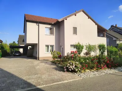 a house with flowers in front of a driveway at Apartma WALK in in Brežice