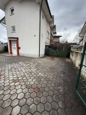 a white building with a gate next to a brick road at Trnovo Lunca Apartment in Ljubljana
