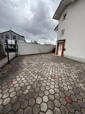 a brick driveway with a white building and a fence at Trnovo Lunca Apartment in Ljubljana
