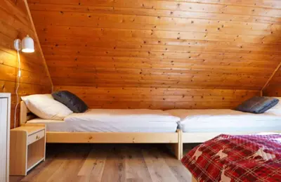 two beds in a room with a wooden wall at Chalet Slavko in Bohinjska Bistrica