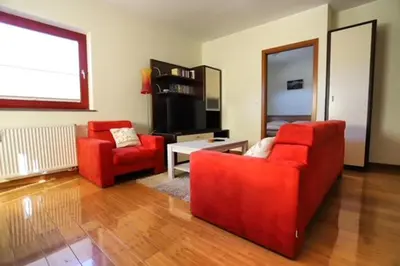 a living room with two red chairs and a television at Apartment Harper in Bohinj