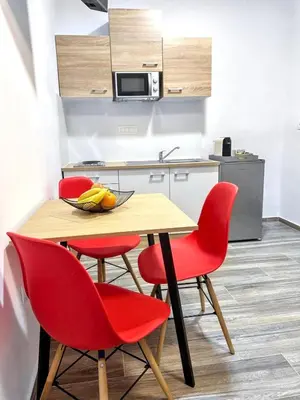 a kitchen with a table and four red chairs at Vesna Studios in Ljubljana