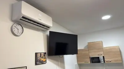 a clock on a wall with a tv and a clock at Vesna Studios in Ljubljana
