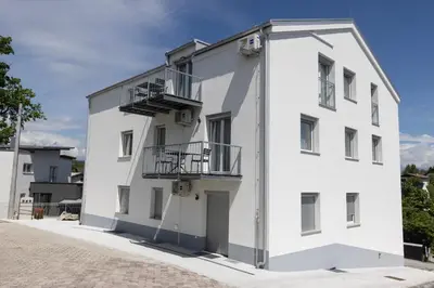 a white building with balconies on a street at Villa Andrea Apartments - Ljubljana in Ljubljana