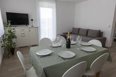 a dining room table with white chairs and a couch at Villa Andrea Apartments - Ljubljana in Ljubljana