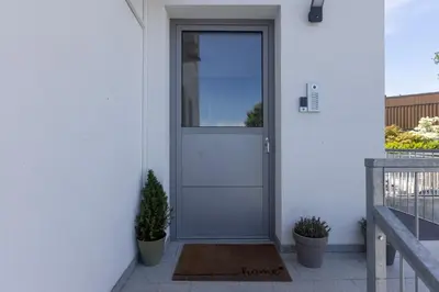 a white door on a white house with plants at Villa Andrea Apartments - Ljubljana in Ljubljana