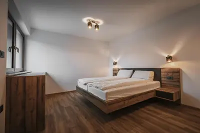 a bedroom with a large bed with white walls and wooden floors at Villa Brje with Seasonal Pool in Dobravlje