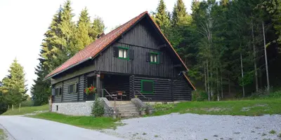 a black barn with green windows on a road at Brunarica Petric - Bela krajina - Komarna vas - Smučišče Gače - Semič in Komarna Vas