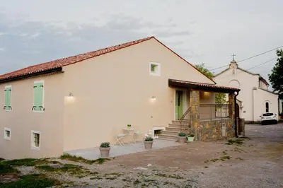 a white house with a staircase and a table at Hiša Skala Kubed in Gračišče