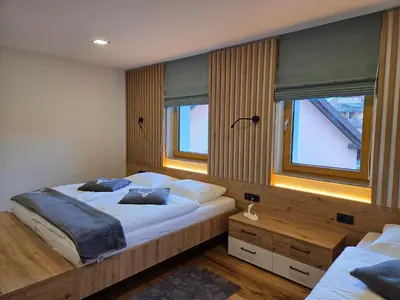 a bedroom with a large bed and two windows at Vila Natalia in Kranjska Gora
