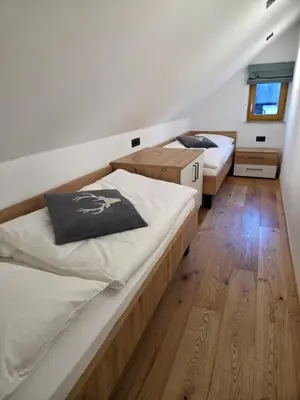 two beds in a room with wooden floors at Vila Natalia in Kranjska Gora