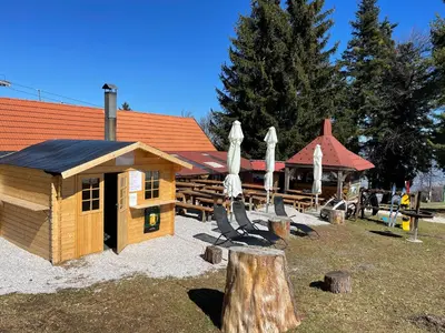 a cabin with chairs and umbrellas in front of a building at Chalet on Pohorje hill Maribor bike park next to the downhill track in Pohorje