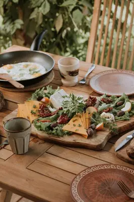 a wooden table with a pizza with cheese and vegetables at Private Eco Cottage in Nature in Šulinci