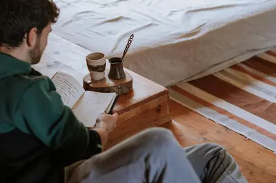 a man sitting on the floor reading a book at Private Eco Cottage in Nature in Šulinci