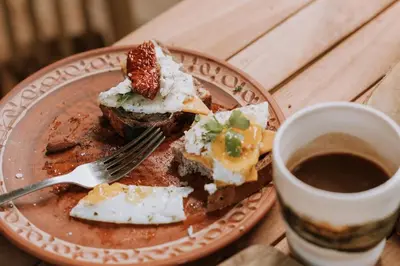 a plate of food with a fork and a cup of coffee at Private Eco Cottage in Nature in Šulinci