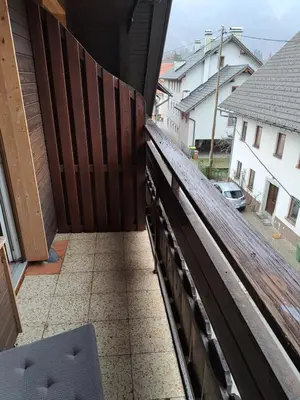 a balcony with a wooden fence and a sidewalk at Hiša Bistrica in Bohinj