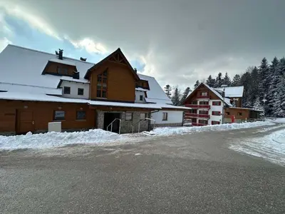 a building with snow on the side of a road at BOLFI LUX Apartma z balkonom in Pohorje