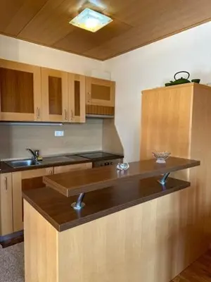 a kitchen with wooden cabinets and a counter top at BOLFI LUX Apartma z balkonom in Pohorje