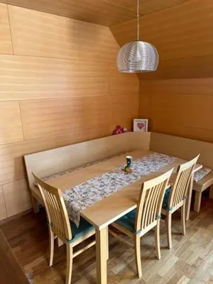 a dining room table with chairs and a table and a lamp at BOLFI LUX Apartma z balkonom in Pohorje
