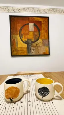 two coffee cups on a table in front of a painting at Hiša Manira in Ajdovščina