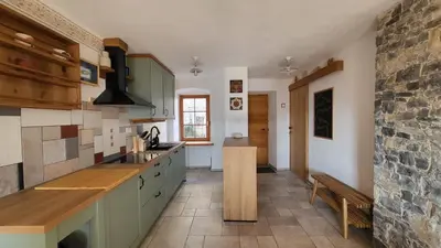 a kitchen with green cabinets and a stone wall at Hiša Manira in Ajdovščina