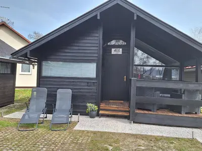 a black house with two chairs and a door at Spa Cottage the Moon house Terme Čatež in Čatež ob Savi